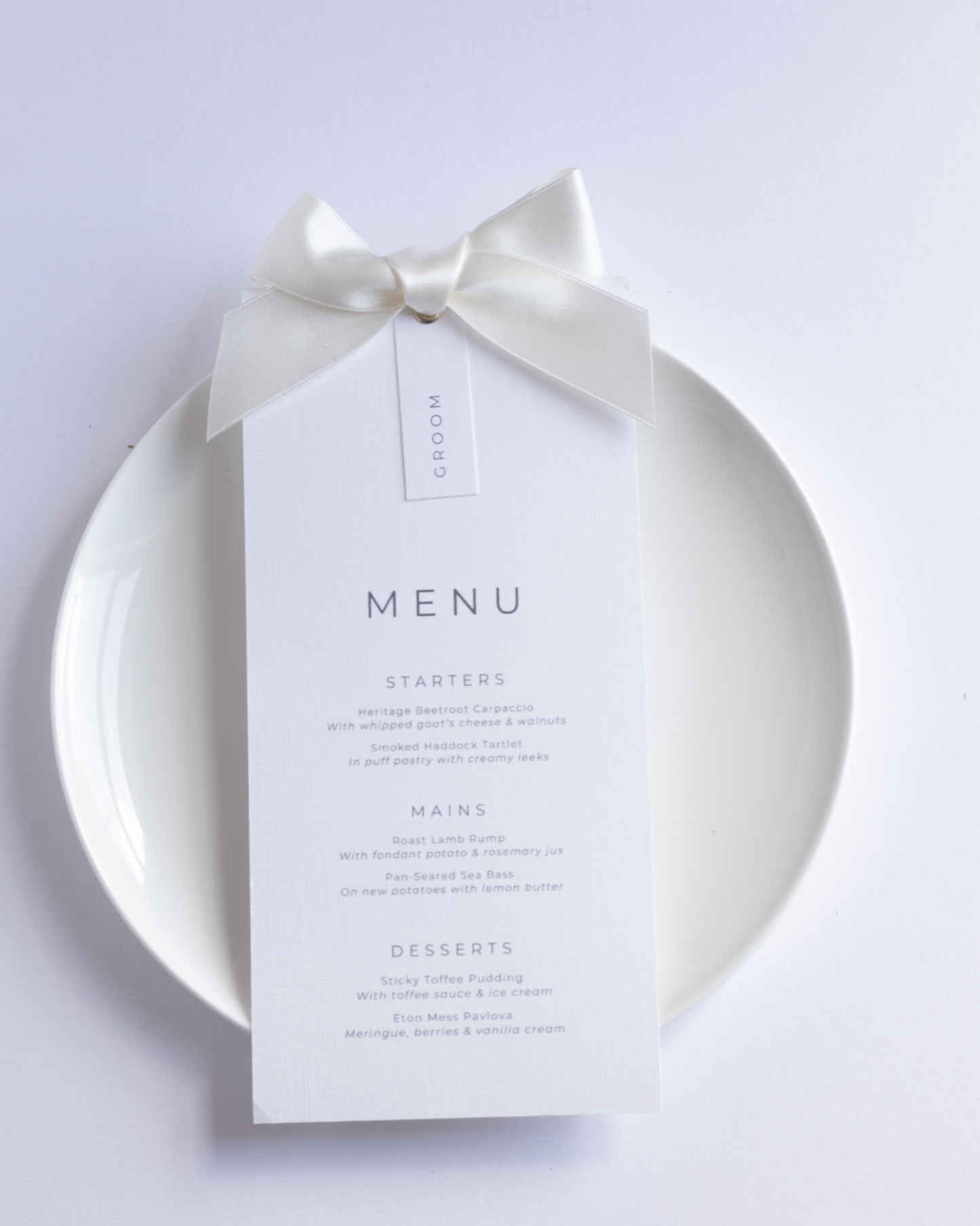 White wedding menu card with an ivory bow on a white plate
