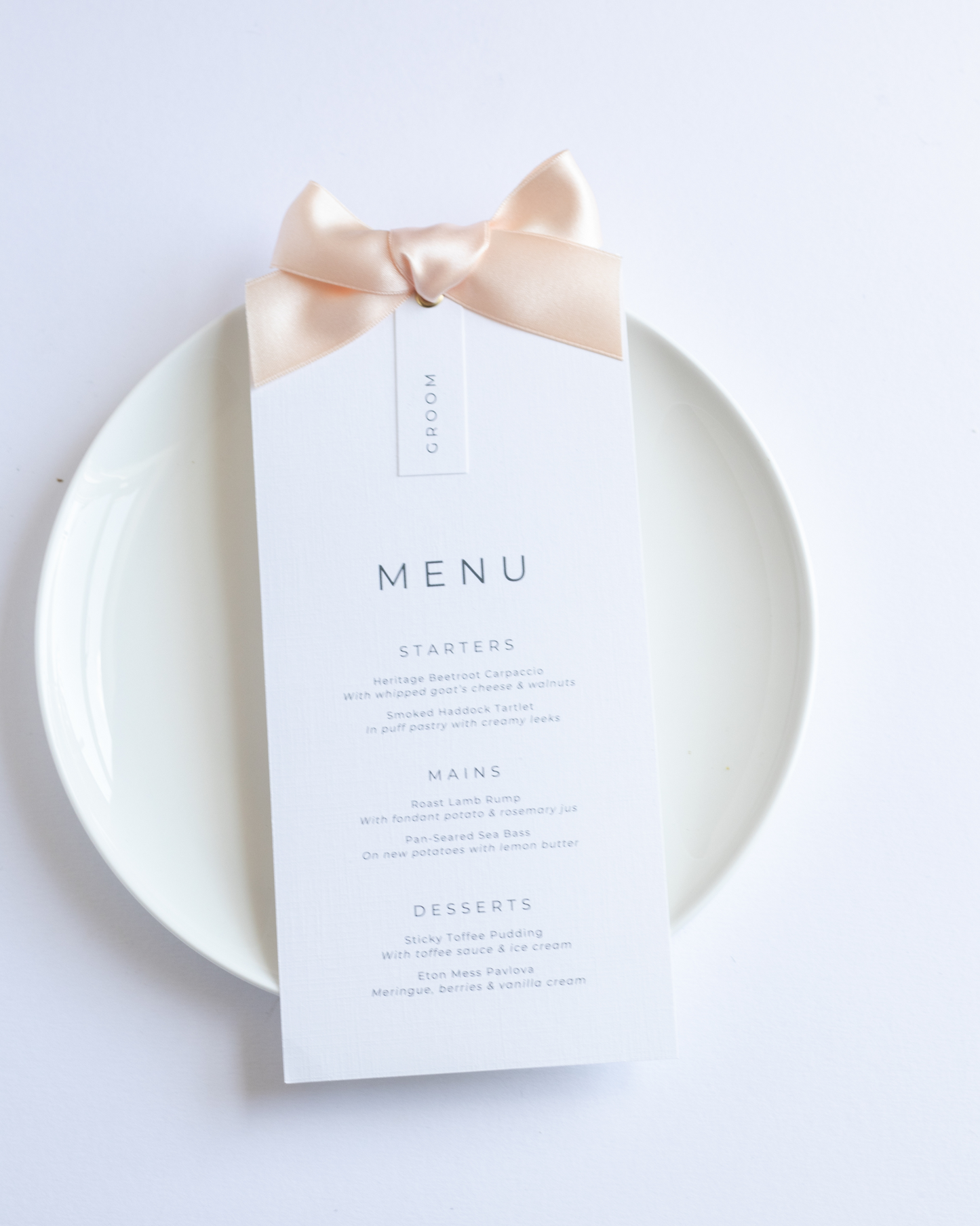 Wedding Menu card with a peach satin ribbon on a white plate